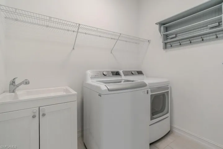 Laundry area with separate washer and dryer and light tile patterned floors