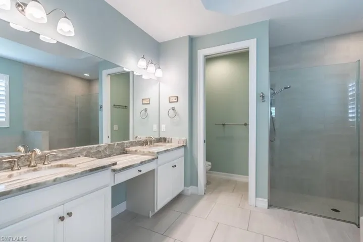 Full bathroom featuring double vanity, tiled shower, and tile patterned floors
