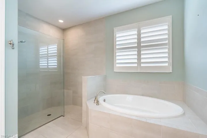 Bathroom with a bath, walk in shower, recessed lighting, and tile patterned flooring
