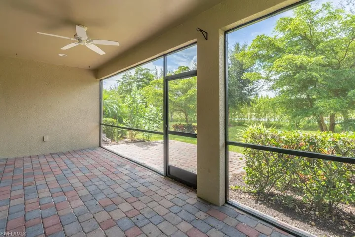 Unfurnished sunroom with a ceiling fan and view of wooded area