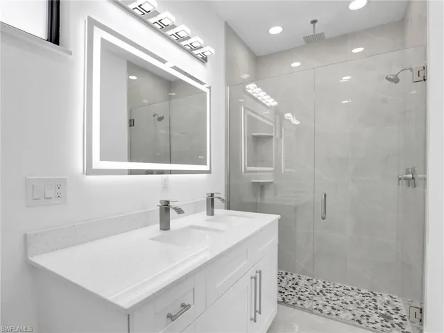 Bathroom with a sink, recessed lighting, a stall shower, and double vanity