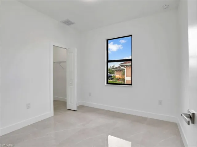 Unfurnished bedroom with a walk in closet, baseboards, visible vents, and a closet