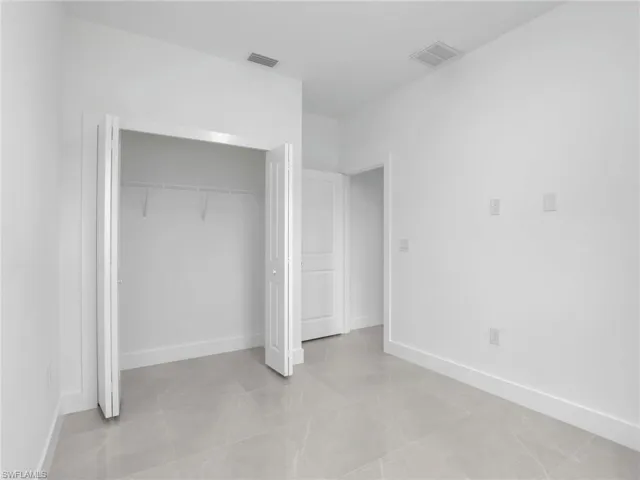 Unfurnished bedroom featuring baseboards, visible vents, and a closet
