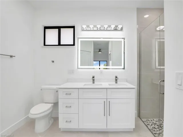 Bathroom with baseboards, vanity, toilet, and a shower stall