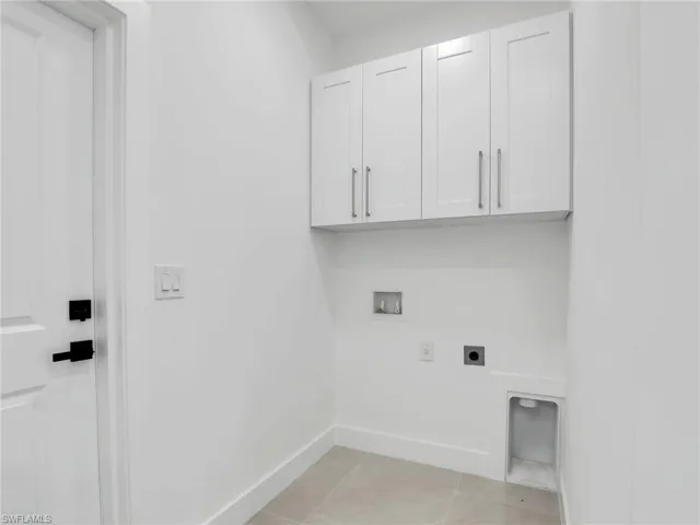 Laundry area featuring hookup for a washing machine, light tile patterned floors, baseboards, cabinet space, and electric dryer hookup
