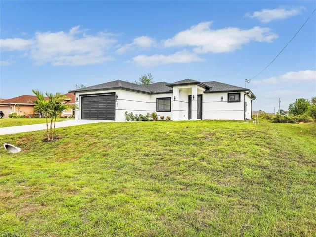 Prairie-style house featuring a front lawn, concrete driveway, and a garage