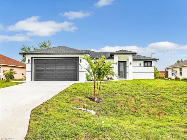 Prairie-style home featuring stucco siding, a front lawn, concrete driveway, an attached garage, and a shingled roof