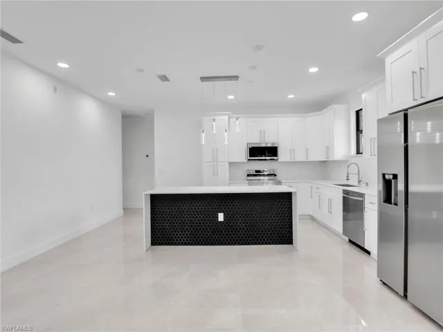 Kitchen featuring a center island, recessed lighting, appliances with stainless steel finishes, white cabinets, and light countertops