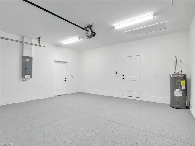 Garage featuring electric panel, a garage door opener, and water heater