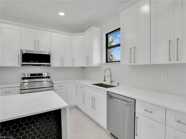 Kitchen with white cabinetry, backsplash, appliances with stainless steel finishes, and a sink