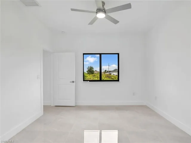 Empty room with light tile patterned flooring, visible vents, baseboards, and ceiling fan