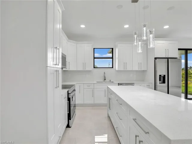 Kitchen with a sink, a kitchen island, backsplash, white cabinetry, and appliances with stainless steel finishes