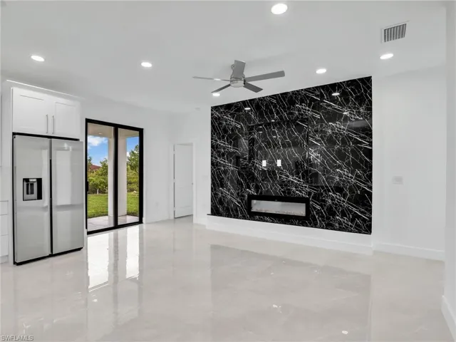 Unfurnished living room featuring visible vents, an accent wall, recessed lighting, marble finish floor, and tile walls