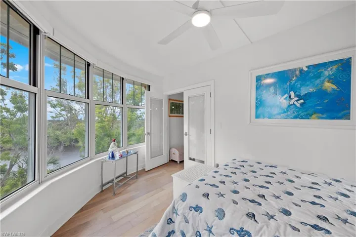 Bedroom with ceiling fan, light hardwood / wood-style flooring, and a water view
