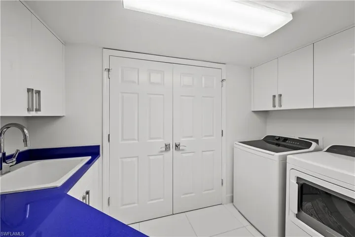Laundry room featuring cabinets, sink, separate washer and dryer, and light tile patterned flooring