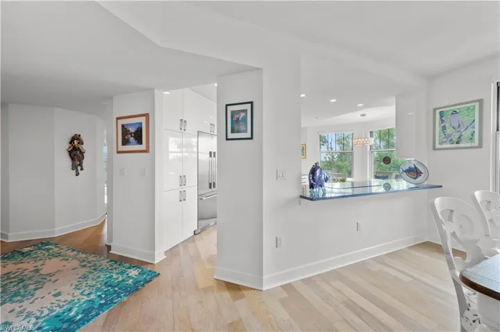 Kitchen with white cabinetry, light hardwood / wood-style flooring, kitchen peninsula, and hanging light fixtures