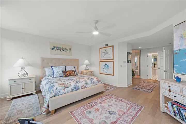 Bedroom with light hardwood / wood-style floors, ensuite bathroom, and ceiling fan