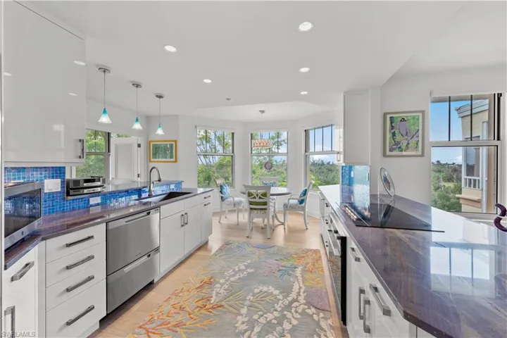Kitchen with sink, white cabinetry, pendant lighting, and decorative backsplash