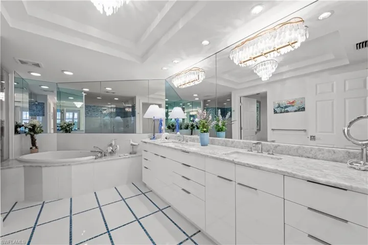Bathroom with a notable chandelier, shower with separate bathtub, a raised ceiling, and vanity