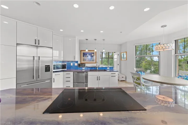 Kitchen featuring white cabinets, decorative backsplash, hanging light fixtures, and appliances with stainless steel finishes