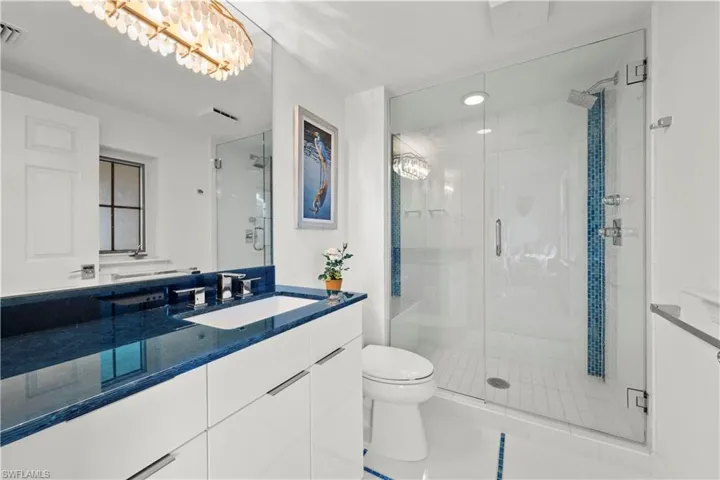 Bathroom with a shower with shower door, tile patterned floors, vanity, and toilet