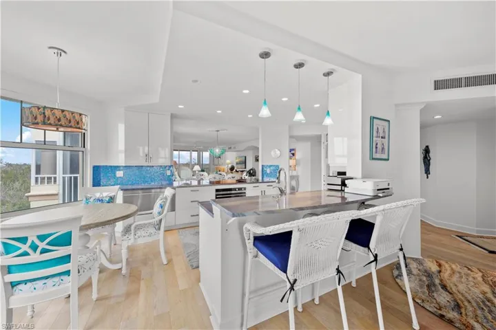 Kitchen featuring pendant lighting, white cabinetry, decorative backsplash, kitchen peninsula, and a breakfast bar