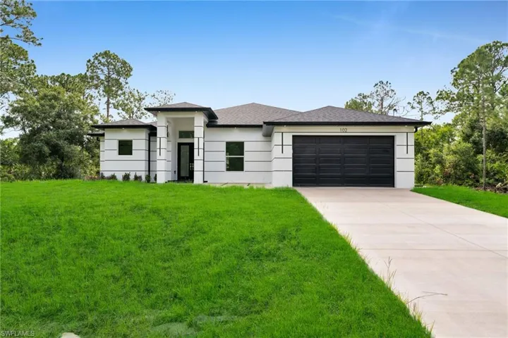 Prairie-style home featuring a front lawn, concrete driveway, an attached garage, and a shingled roof