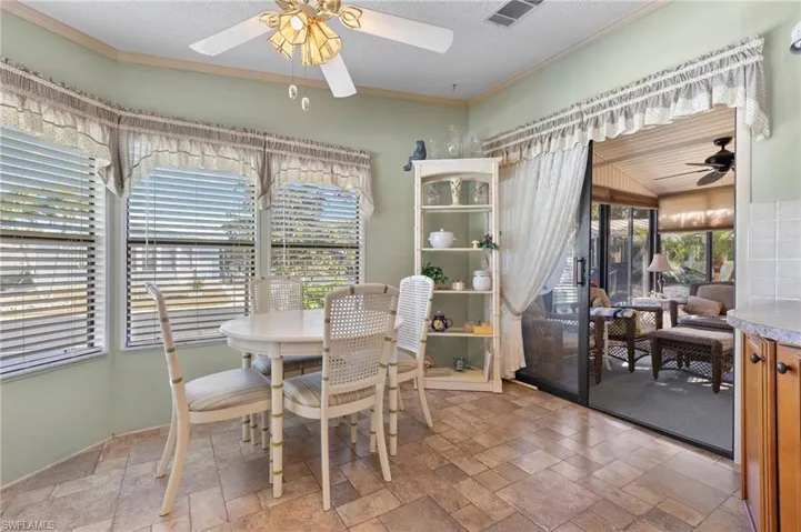Dining space featuring a wealth of natural light, crown molding, visible vents, and stone tile flooring