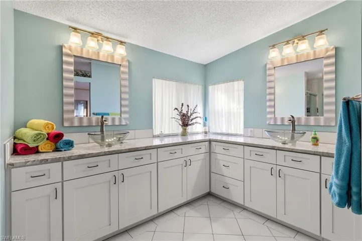 Full bath featuring tile patterned flooring, a sink, a textured ceiling, and double vanity