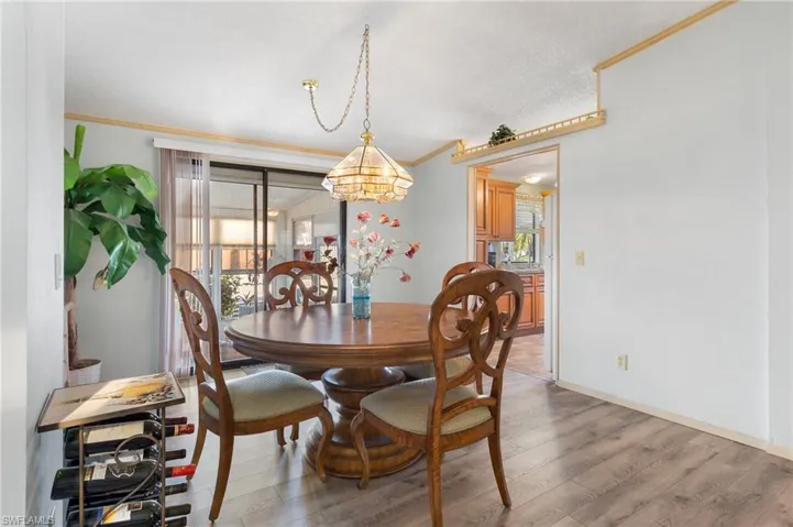 Dining room with baseboards, plenty of natural light, wood finished floors, and crown molding
