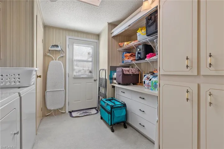 Laundry area featuring cabinet space, a textured ceiling, washer and dryer, and light colored carpet