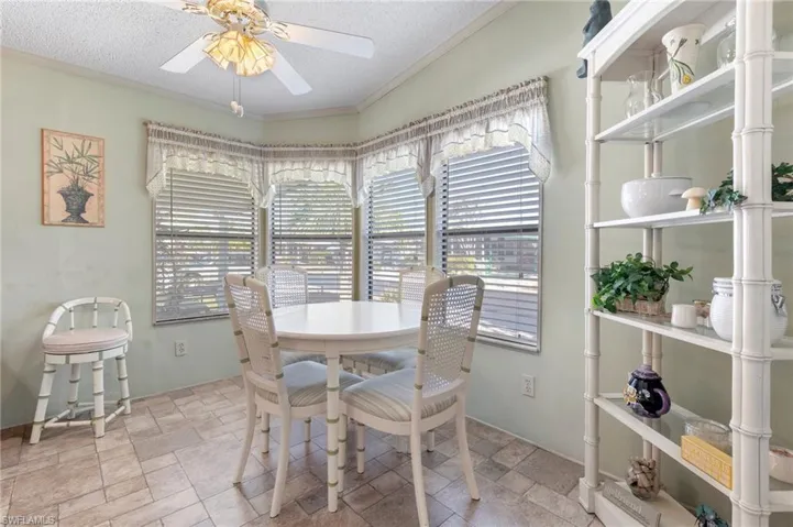 Dining area featuring ornamental molding, stone tile flooring, and a textured ceiling