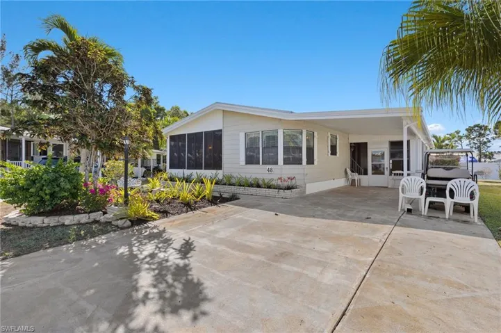 View of front of property with an attached carport, a sunroom, and driveway