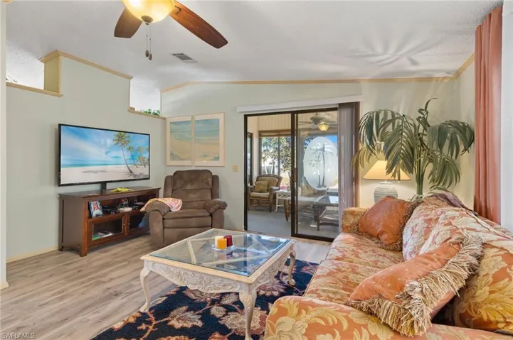 Living room featuring lofted ceiling, light wood-style flooring, visible vents, and a ceiling fan