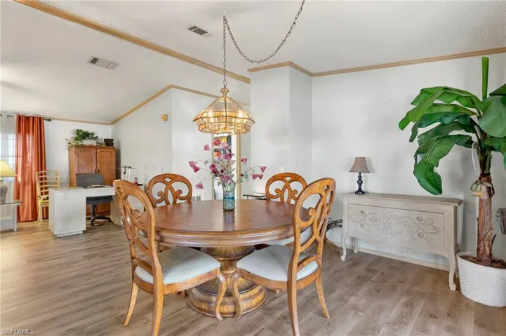 Dining space with visible vents, light wood-style flooring, and crown molding