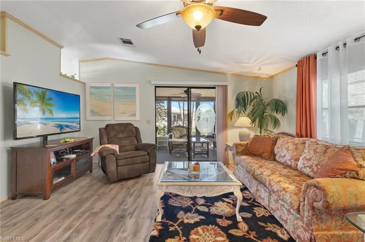 Living area featuring lofted ceiling, a textured ceiling, visible vents, and light wood-style floors