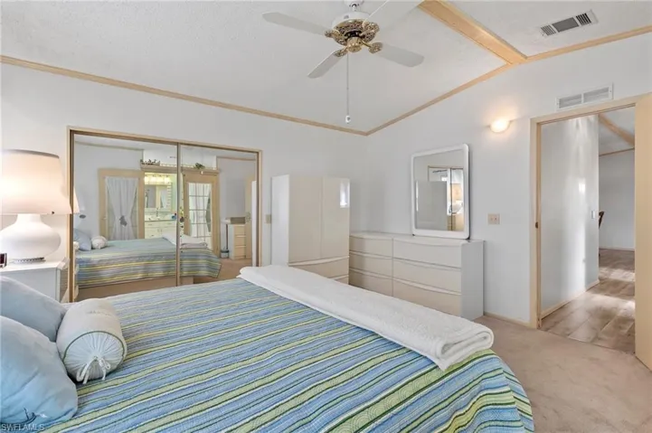 Bedroom with lofted ceiling, carpet floors, visible vents, and a textured ceiling