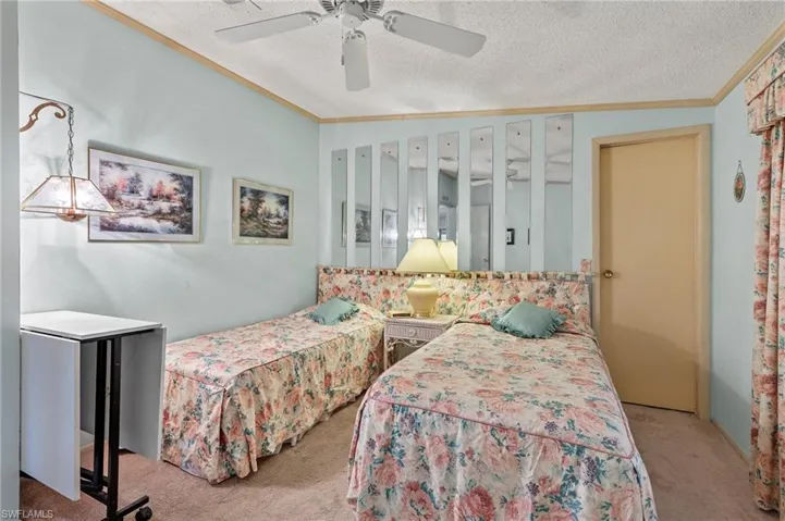 Bedroom featuring light colored carpet, crown molding, a textured ceiling, and ceiling fan