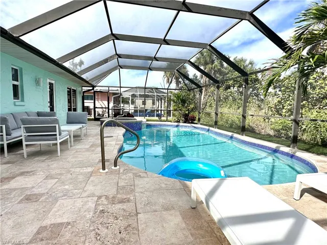 View of swimming pool featuring a pool with connected hot tub, a patio, a sunroom, glass enclosure, and an outdoor living space