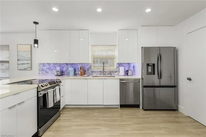 Kitchen featuring modern cabinets, stainless steel appliances, backsplash, white cabinetry, and recessed lighting