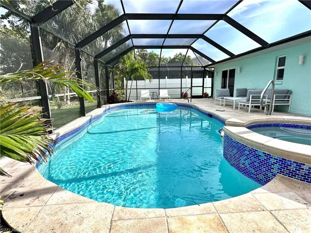 View of pool featuring a sunroom, a patio area, glass enclosure, and a pool with connected hot tub