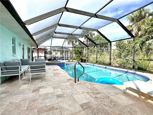 View of pool with a sunroom, glass enclosure, a patio, a pool with connected hot tub, and an outdoor hangout area
