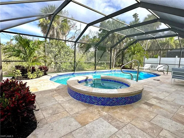 View of pool with a sunroom, a patio, a pool with connected hot tub, and glass enclosure