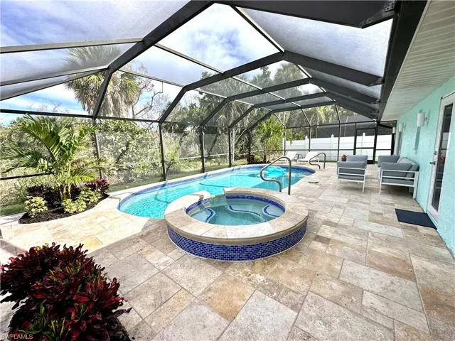View of swimming pool with a patio, a sunroom, a pool with connected hot tub, and a lanai