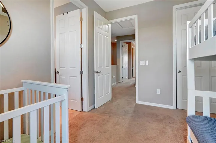 Bedroom with attic access, light carpet, and a crib