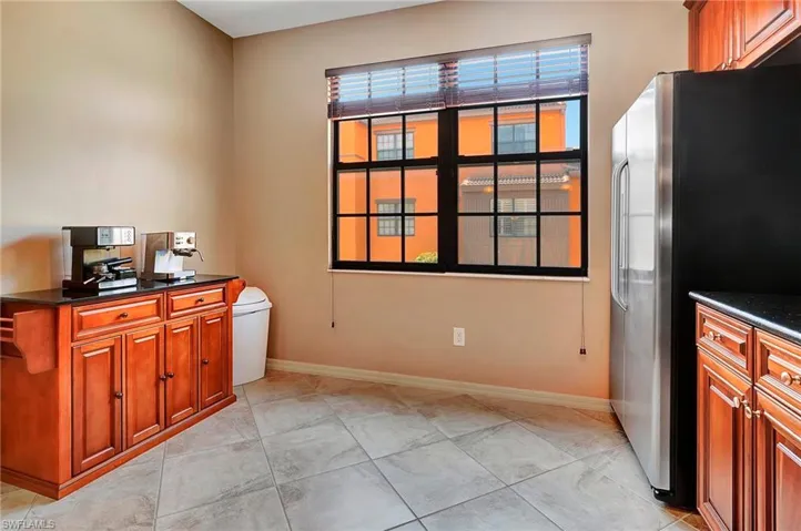 Kitchen with freestanding refrigerator, dark countertops, and brown cabinets