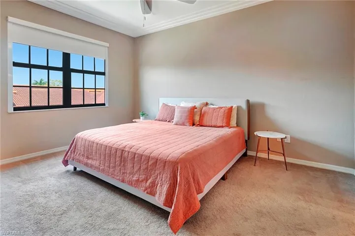 Carpeted bedroom featuring ornamental molding and a ceiling fan