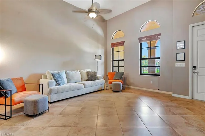 Living area featuring ceiling fan, high vaulted ceiling, and light tile patterned floors