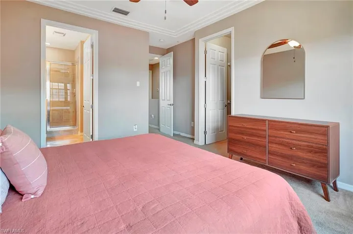 Bedroom featuring ensuite bath, carpet floors, and a ceiling fan
