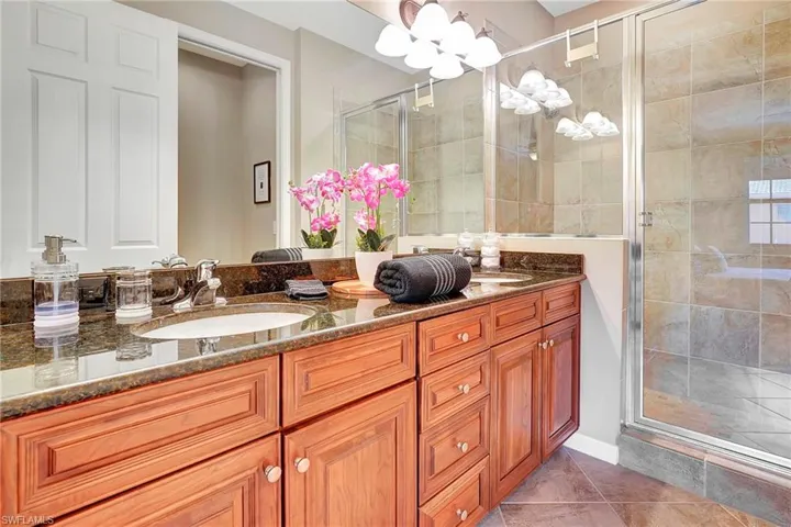 Full bathroom featuring double vanity and a shower stall